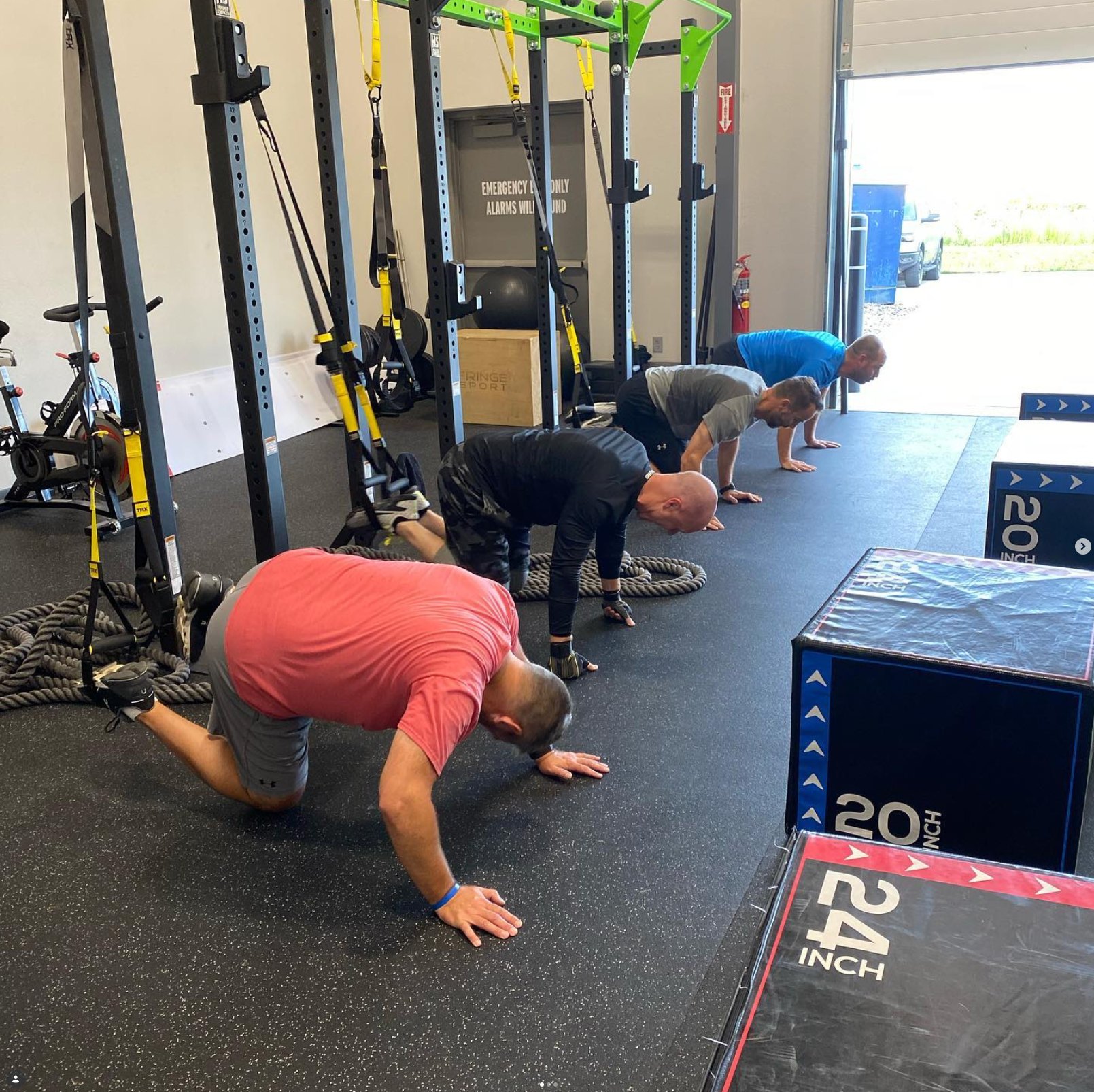 Adult strength class doing bear crawls across the floor at Motivera