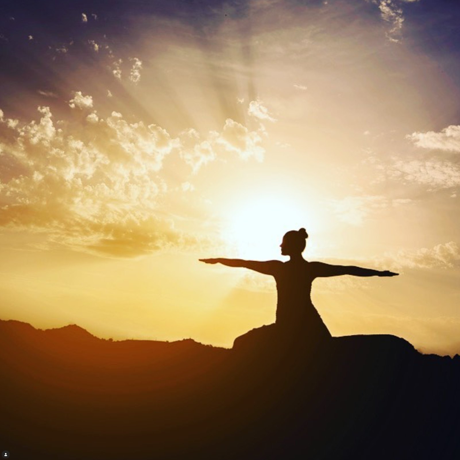 Rachel silhouetted in a warrior yoga pose against a sunset